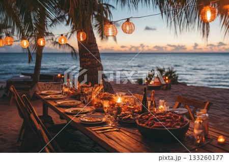 Romantic Beach Dinner at Sunset with Lanterns and Delicious Food Setup 133260177