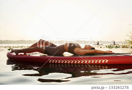 Relaxing, lying down. Young woman is with the sup board on the lake 133261278