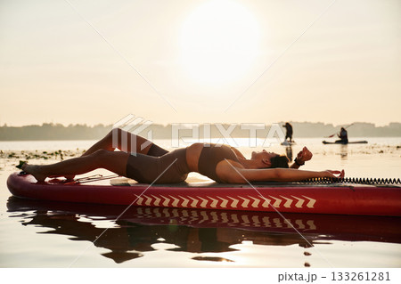 Relaxing, lying down. Young woman is with the sup board on the lake 133261281