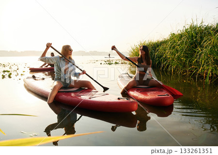 Active weekend, on the water. Women friends are on sup board on the lake together 133261351