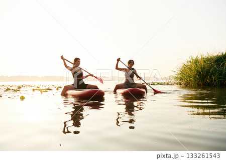 Sport conception. Women friends are on sup board on the lake together Sport conception. Women friends are on sup board on the lake together 133261543