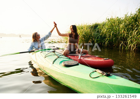 Women friends are on sup board on the lake together Women friends are on sup board on the lake together 133261549