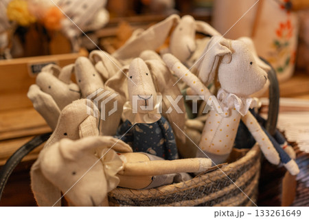 Handmade fabric rabbit toys arranged in a cozy display. Soft textile materials, warm tones and charming handcrafted details create a rustic decorative scene 133261649