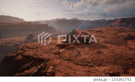 Sunset casts a warm glow over vast rock formations in a desert canyon. The rugged terrain showcases natures beauty as shadows lengthen across the landscape, inviting exploration and wonder. Sunset casts a warm glow over vast rock formations in a desert canyon. The rugged terrain showcases natures beauty as shadows lengthen across the landscape, inviting exploration and wonder. 133261751