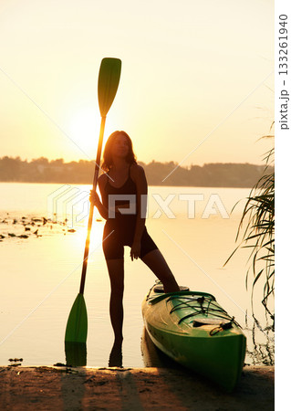 With an oar in her hand, against sunset. Young woman is with the sup board on the lake 133261940