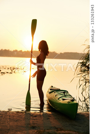 With an oar in her hand, against sunset. Young woman is with the sup board on the lake With an oar in her hand, against sunset. Young woman is with the sup board on the lake 133261943