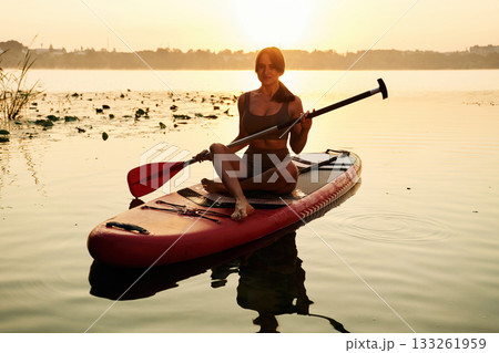 Peaceful sunset time. Young woman is with the sup board on the lake Peaceful sunset time. Young woman is with the sup board on the lake 133261959