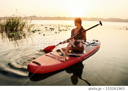 Peaceful sunset time. Young woman is with the sup board on the lake Peaceful sunset time. Young woman is with the sup board on the lake 133261963