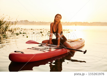 Positive, joyful facial expression. Young woman is with the sup board on the lake Positive, joyful facial expression. Young woman is with the sup board on the lake 133261976