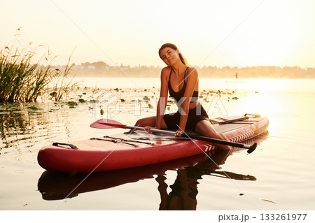 Positive, joyful facial expression. Young woman is with the sup board on the lake 133261977
