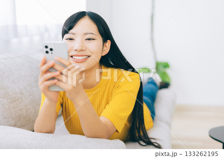 ソファに寝転がってスマホを使う女性 ソファに寝転がってスマホを使う女性 133262195