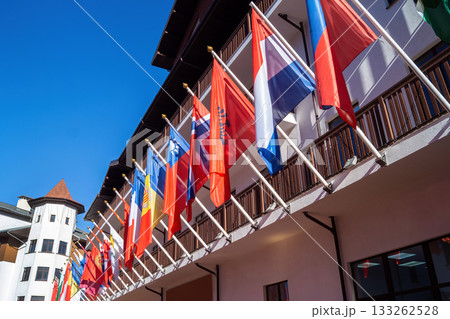 Vibrant display of international flags at a resort in the mountains under a clear blue sky 133262528