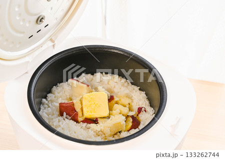 炊きあがったサツマイモご飯にバターを加える 133262744