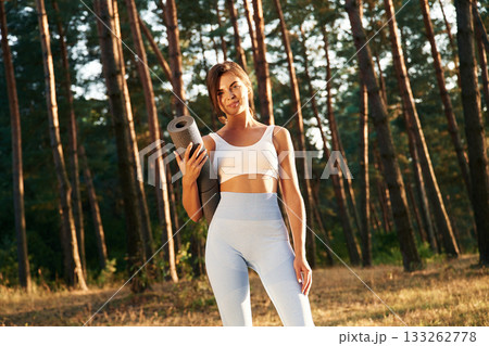 Ready for training, holding mat. Woman is doing yoga fitness exercises in the forest Ready for training, holding mat. Woman is doing yoga fitness exercises in the forest 133262778