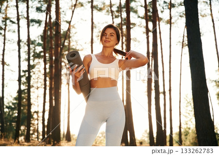 Model is posing with mat in hand. Woman is doing yoga fitness exercises in the forest Model is posing with mat in hand. Woman is doing yoga fitness exercises in the forest 133262783