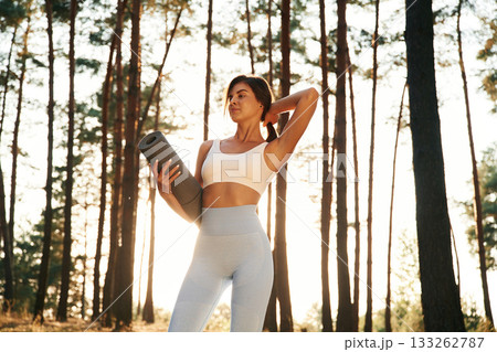 Always ready for training, holding mat. Woman is doing yoga fitness exercises in the forest 133262787