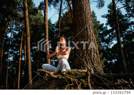 On the roots of the tree. Woman is doing yoga fitness exercises in the forest On the roots of the tree. Woman is doing yoga fitness exercises in the forest 133262794