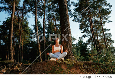 Standard lotus pose. Woman is doing yoga fitness exercises in the forest Standard lotus pose. Woman is doing yoga fitness exercises in the forest 133262800