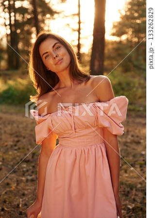 Front view. Pretty young woman in pink dress is in the forest 133262829