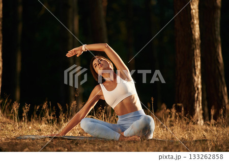 Sitting in lotus pose. Woman is doing yoga fitness exercises in the forest Sitting in lotus pose. Woman is doing yoga fitness exercises in the forest 133262858