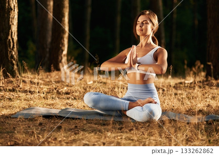 Lotus pose. Woman is doing yoga fitness exercises in the forest Lotus pose. Woman is doing yoga fitness exercises in the forest 133262862