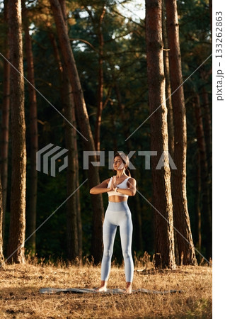 Wellbeing outdoors. Woman is doing yoga fitness exercises in the forest 133262863