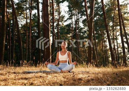 Meditation, calm mind. Woman is doing yoga fitness exercises in the forest 133262880