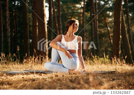 On the mat. Woman is doing yoga fitness exercises in the forest On the mat. Woman is doing yoga fitness exercises in the forest 133262887