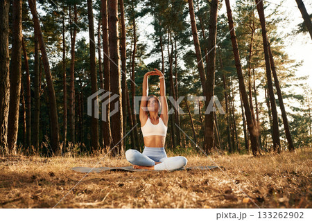 Hands are up, warm up. Woman is doing yoga fitness exercises in the forest Hands are up, warm up. Woman is doing yoga fitness exercises in the forest 133262902