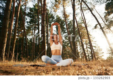 Hands are up, warm up. Woman is doing yoga fitness exercises in the forest Hands are up, warm up. Woman is doing yoga fitness exercises in the forest 133262903