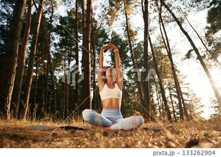 Hands are up, warm up. Woman is doing yoga fitness exercises in the forest Hands are up, warm up. Woman is doing yoga fitness exercises in the forest 133262904