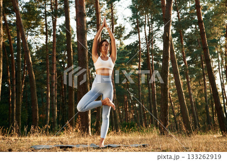 On one leg, standing. Woman is doing yoga fitness exercises in the forest 133262919