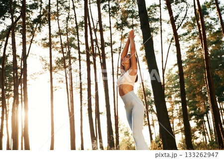 Stretching up, warm up exercises. Woman is doing yoga fitness exercises in the forest 133262947