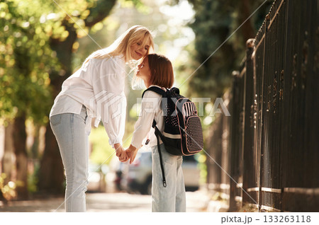 Holding the hands. Schoolgirl with her mother are outdoors together 133263118