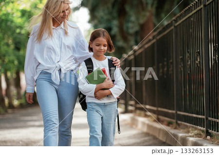 Smiling, positive emotions. Schoolgirl with her mother are outdoors together Smiling, positive emotions. Schoolgirl with her mother are outdoors together 133263153