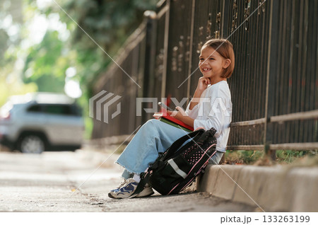 On the sidewalk. Schoolgirl with backpack is outdoors 133263199