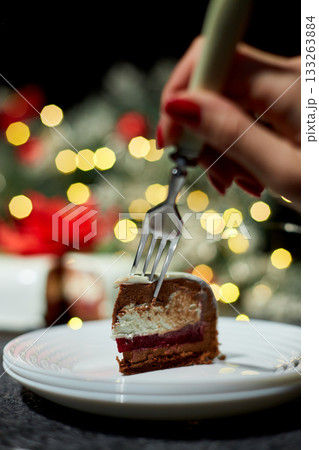 A Hand Reaching for a Slice of Decadent Layered Dessert on a Festive Table Decorated With Twinkling Lights During the Holiday Season 133263884