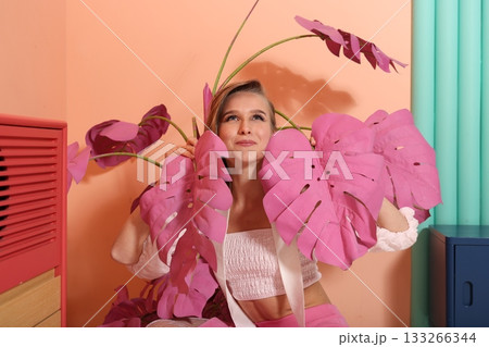 Creative stylist with pink monstera leaves, blonde woman Creative stylist with pink monstera leaves, blonde woman 133266344
