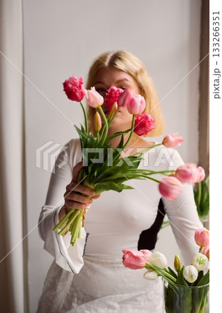 Elegant portrait of woman partially concealing face among flowers Elegant portrait of woman partially concealing face among flowers 133266351