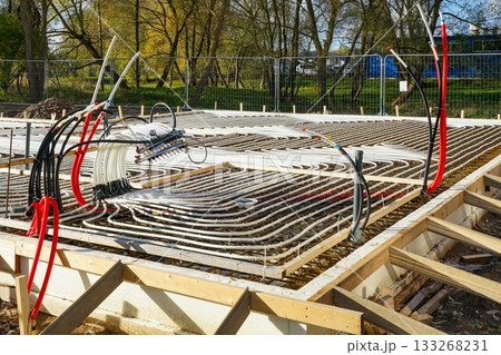 Underfloor heating system installation with plastic pipes in concrete base, house construction site Underfloor heating system installation with plastic pipes in concrete base, house construction site 133268231