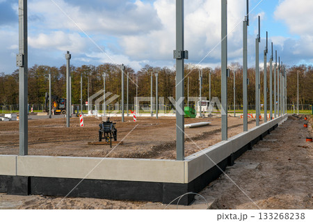 Steel frame columns installed on concrete foundation at large commercial construction site 133268238