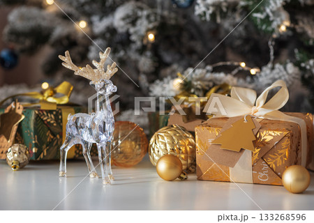 Crystal Reindeer with Gold Antlers and Christmas Gifts in Festive Interior 133268596