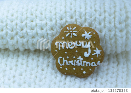 Gingerbread cookie decorated with royal icing on white knitted background. Merry Christmas Gingerbread cookie decorated with royal icing on white knitted background. Merry Christmas 133270358