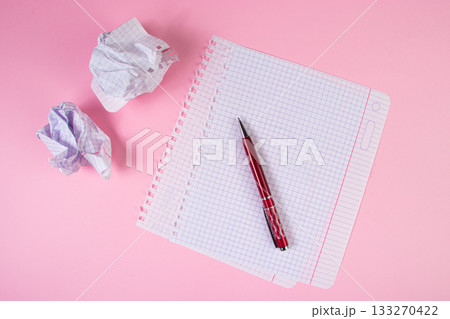Blank paper and crumpled paper wads on a pink background. Symbol of writing. Search for inspiration, writing plans. Education or business concept. Blank paper and crumpled paper wads on a pink background. Symbol of writing. Search for inspiration, writing plans. Education or business concept. 133270422