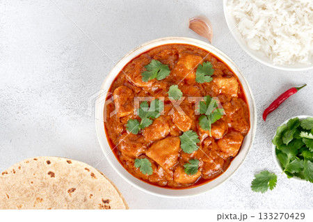 Butter chicken in creamy spiced sauce with fresh cilantro, rice and roti. Top view on white background. Indian food 133270429