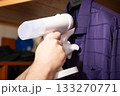 Handheld Steamer Ironing Purple Shirt in White Glove at Home 133270771