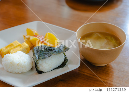おにぎりと玉子焼き、じゃがいもの炒め物を盛り付けた和朝食と味噌汁 133271389