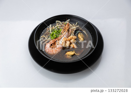 Seafood ramen with prawn, mussels and noodles in soy broth, black bowl on white background 133272028