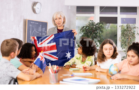 Female teacher showing australian flag to kids in geography class Female teacher showing australian flag to kids in geography class 133272922