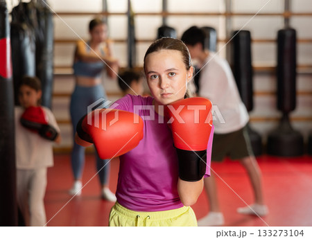 Girl posing during training in boxing gloves Girl posing during training in boxing gloves 133273104
